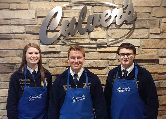 Three FFA members stand in front of a Culver's sign in their blue jackets and Culver's aprons